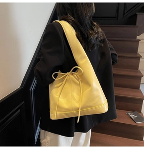 Grand sac cabas jaune pâle avec un nœud porté à l'épaule par un mannequin chic