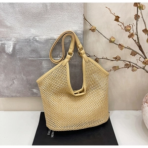 Détail du sac cabas en paille tissée avec anses en cuir et fermeture à boucle en métal