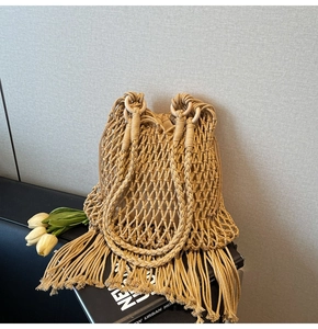 Detailed macro of a khaki bohemian woven tote bag with fringe tassels and ring handles