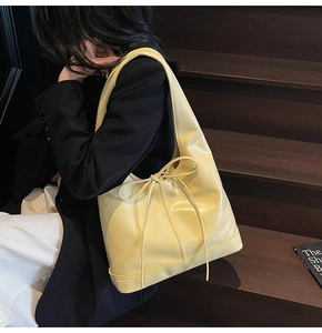 Vue détaillée du sac seau jaune clair avec nœud en cuir dans une scène de style de vie