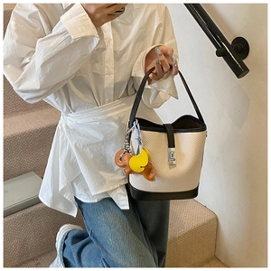 Detail of woven bucket bag with black leather trim and cute animal charms on handle