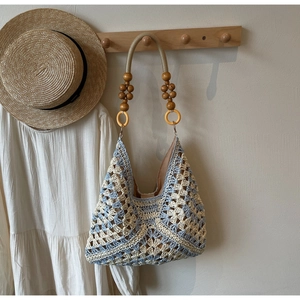 Detailed close-up of woven tote bag with wooden bead handle on a neutral background