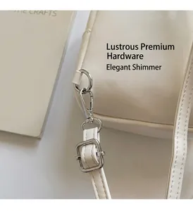Macro detail of silver lobster clasp and hardware on a white quilted leather backpack