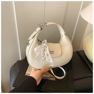Close-up of cream crescent handbag with pleated texture, lace bow and pearl detail
