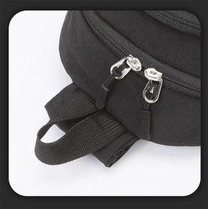 Detail view of the silver double metal zippers and black nylon handle on the sling bag