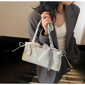 Pale mint green leather bag with lace bow and ribbon shown in a stylish indoor setting