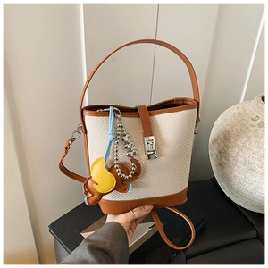 Detail of woven bucket bag with leather handles and a cute elephant charm accessory