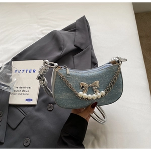 Detail of light blue denim hobo bag featuring rhinestone accents and silver metal bow
