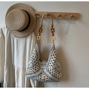 Detail of woven tote bag with crochet flower patterns and decorative wooden bead strap