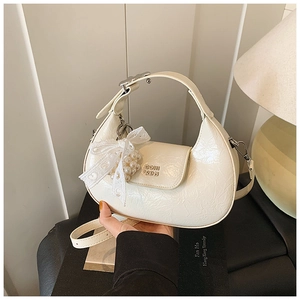 Detail of cream hobo bag with vintage cracked leather texture and pearl lace bow charm
