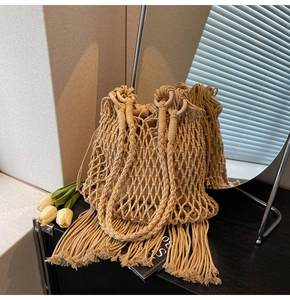 Detail of beige woven bucket bag with long fringe tassels and rustic round handle