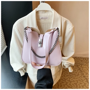 Detail of light purple bucket bag featuring silver rotary lock and chain strap on white suit