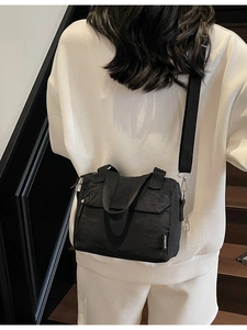 Fashionable black nylon crossbody bag with wide shoulder strap worn by a model