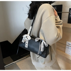 Detailansicht der schwarzen Ledertasche mit weißer Spitze und silbernem Herzanhänger
