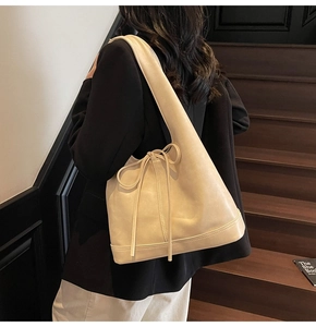 Détail d'un sac hobo en similicuir crème avec des sangles à nœuds et coutures renforcées
