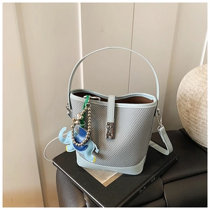 Detailed close-up of light blue woven bucket bag with metal buckle and elephant charm
