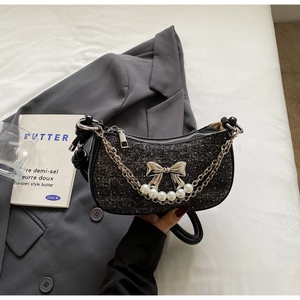 Detailed macro of the black tweed hobo bag with a silver bow and pearl chain accents