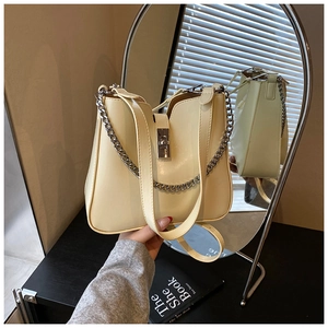 Close-up of cream bucket bag with silver twist lock and decorative metal chain