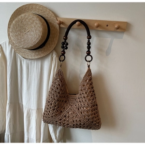 Detail of hand-woven tote bag featuring wooden bead handle and intricate crochet pattern