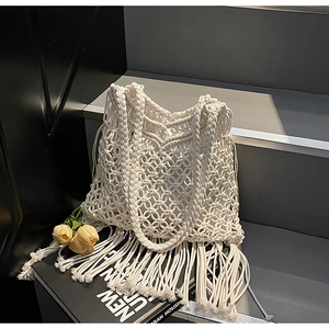 Detailed close-up of handmade white crochet tote bag featuring long bohemian tassels