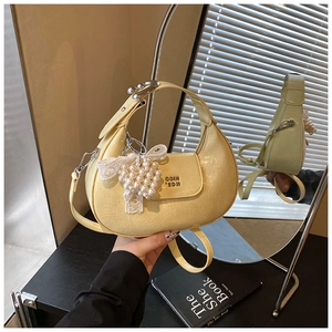 Detail of light yellow crescent bag with pleated texture and pearl cherry charm