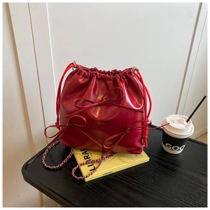 Detail of dark red drawstring bucket bag with decorative bows on a library book