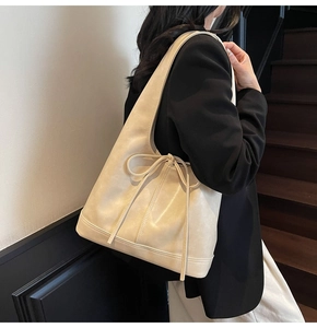 Détail d'un sac à main beige en cuir synthétique avec un élégant nœud décoratif