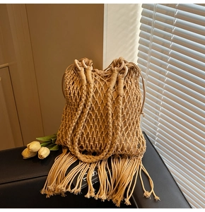 Detail of hand-woven bucket bag with decorative long tassels and round handle