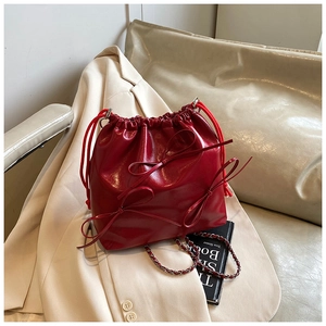 Detail of red drawstring bucket bag featuring metallic texture and 3D bow decorations