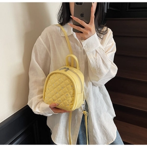 Detail of yellow mini backpack featuring quilted embroidery and sparkling rhinestones