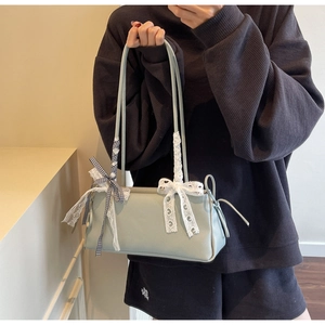Detail of mint green crossbody bag featuring decorative lace and a black gingham bow
