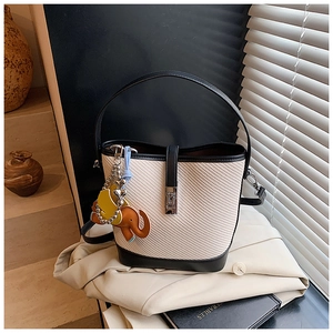 Close-up of contrast bucket bag with woven texture, metal buckle and elephant charm