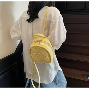 Detail of yellow quilted backpack with rhinestones worn by a model in white shirt