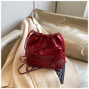 Close-up of red drawstring bucket bag with decorative bows and metal chain strap