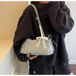Detail of light green leather bag featuring white lace bow and checkered ribbon accents