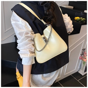 Detail of cream bucket bag showing silver twist lock and decorative chain on a model