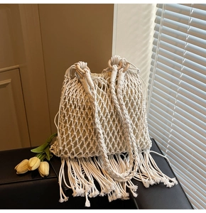 Detail of hand-woven cream bucket bag featuring long tassels and a wooden ring handle