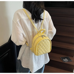 Close-up of a yellow diamond-patterned mini backpack worn on a model's back
