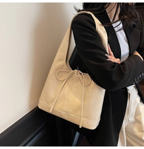 Vue détaillée du sac à bandoulière crème avec nœud décoratif et base renforcée