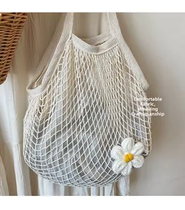 Detail of woven cotton mesh bag featuring a grey drawstring lining and crochet daisy flower