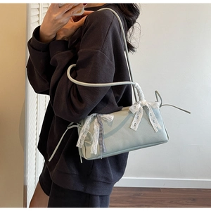 Close-up of light blue leather bag with white lace bow and checkered ribbon details