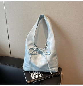 Détail d'un grand sac hobo bleu clair avec nœud décoratif et large bandoulière