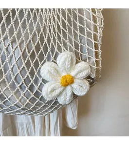 Detail of white cotton mesh bag featuring a woven floral accent and diamond pattern texture