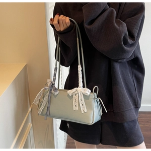 Close-up of mint green lychee pattern shoulder bag with white lace bow on female model