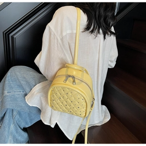 Detail of quilted bright yellow mini backpack with silver rhinestone accents on steps