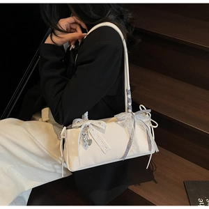 Detail of white litchi pattern baguette bag with lace bow and heart metal pendant