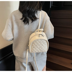 Close-up of cream mini backpack with quilted diamond pattern and rhinestone accents on back