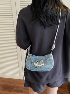 Blue denim half-moon underarm bag with silver bow and pearl strap on model back