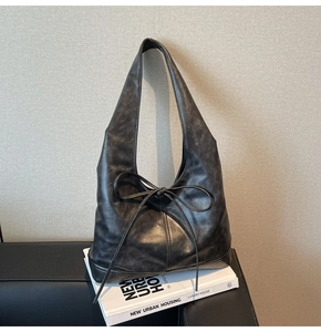 Gros plan du sac cabas noir avec détail nœud et texture en cuir synthétique