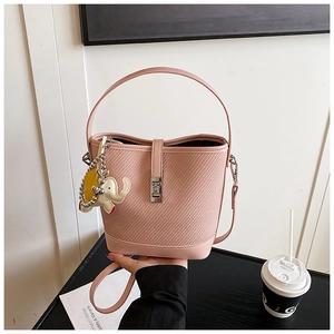 Detail of pink bucket bag with woven texture, metal lock and cute elephant charm